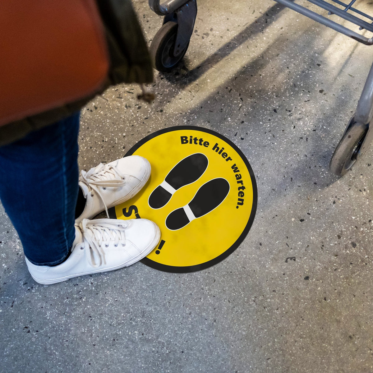 Bodenaufkleber STOP! Bitte hier warten schwarz/gelb im Einsatz auf Betonboden